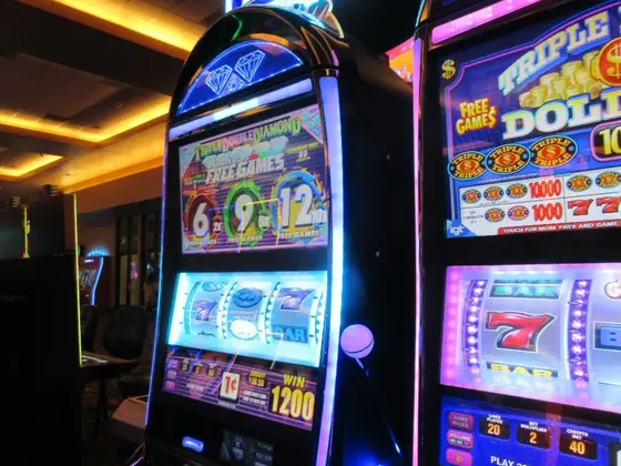 Row of lit-up slot machines in a casino
